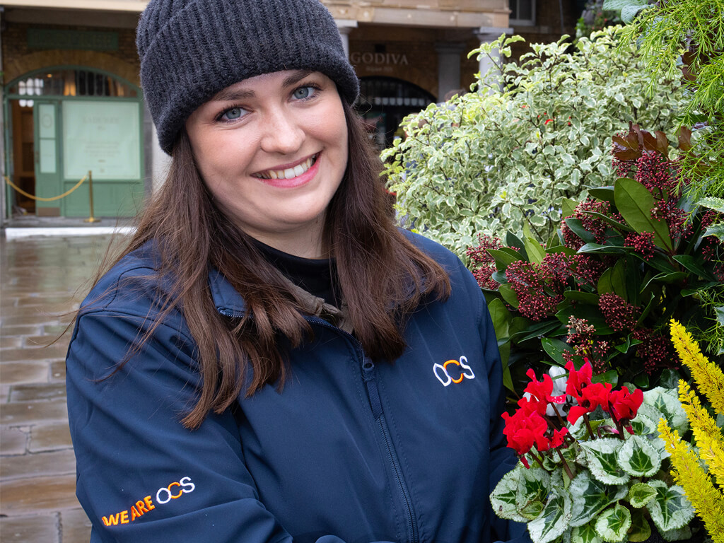 OCS colleague standing alongside flowers