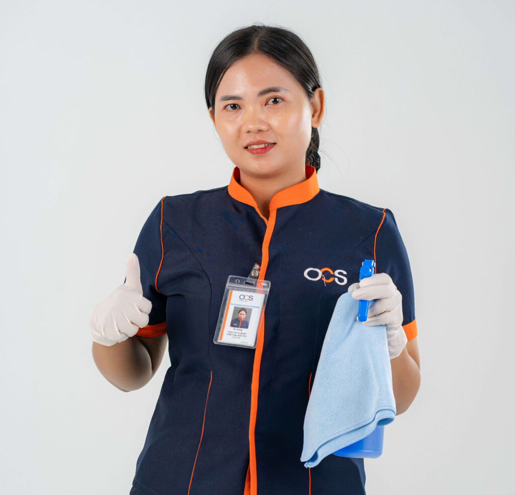 A woman in uniform from OCS Cambodia holds a cleaning cloth, ready to maintain a clean environment alongside her colleagues.