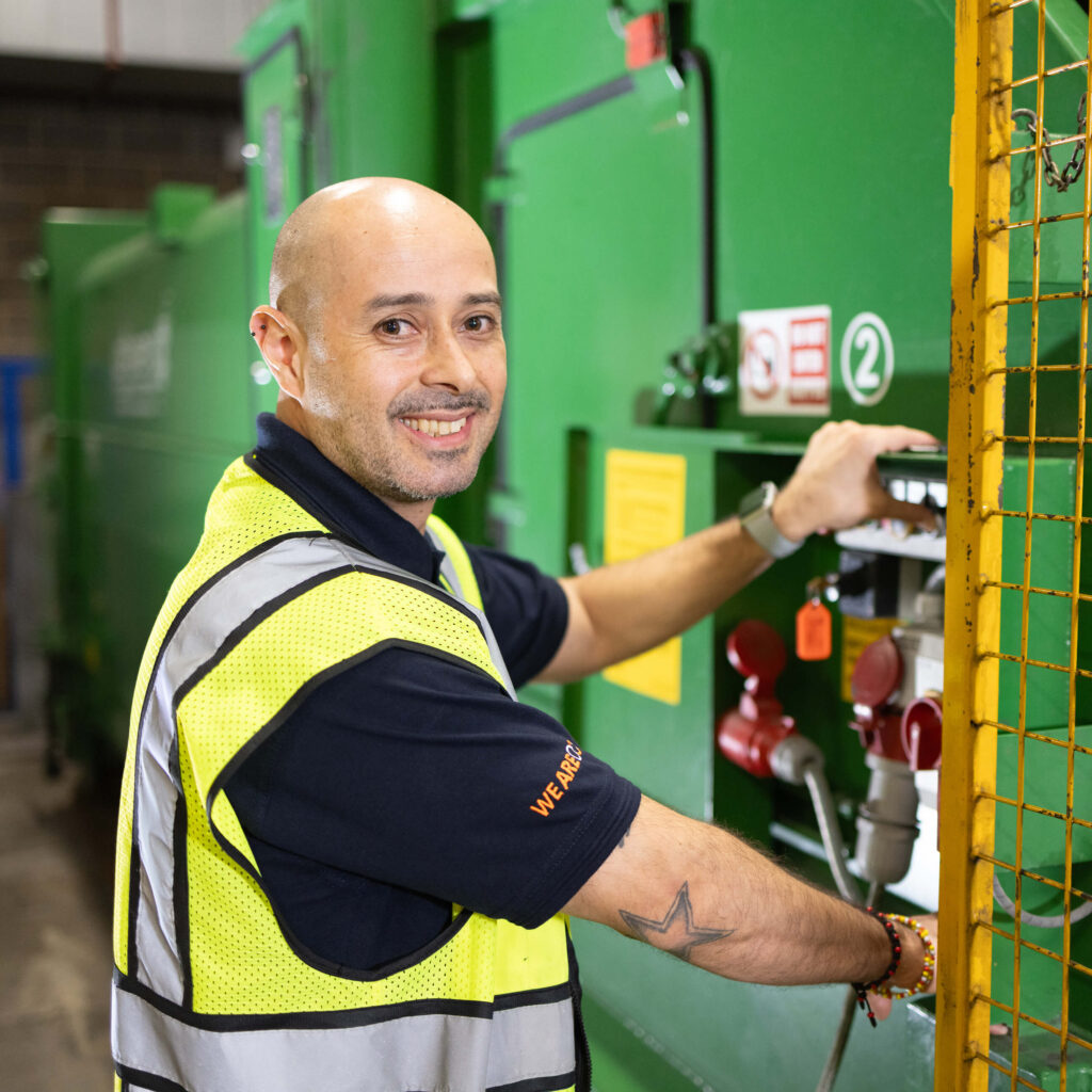 A man in a yellow vest stands confidently, representing OCS hard services in a professional setting.