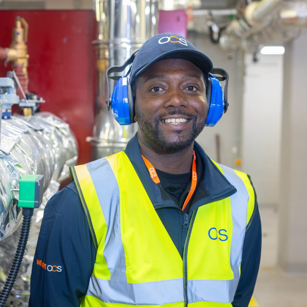 A man in a safety vest and headphones, representing an OCS hard services colleague engaged in his work.