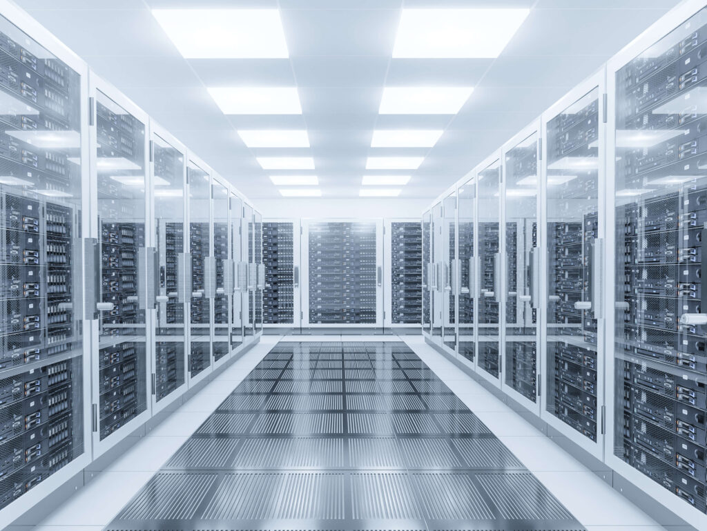 A modern data center with rows of server racks enclosed in glass cabinets on both sides. The floor is reflective with a metallic mesh design, and the ceiling displays bright, evenly spaced square lights, creating a sleek, high-tech atmosphere.