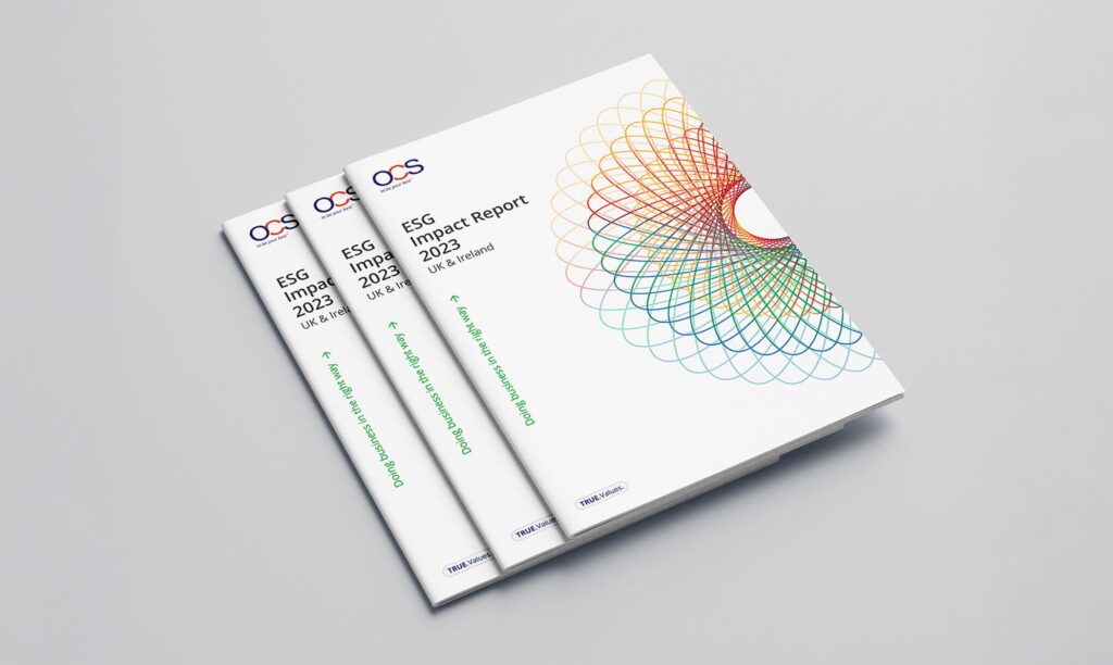 Three ESG Impact Report 2023 booklets with colorful geometric designs on white covers are stacked on a light gray surface. The reports are branded with OCS logos and UK & Ireland region listed.