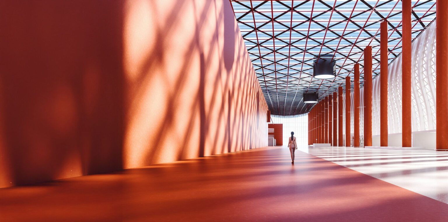 A person walks alone in a large, modern hall with orange walls, tall columns, and a glass ceiling casting geometric shadows on the floor and walls.