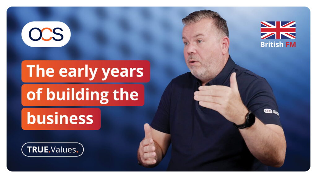 A man gesturing whilst speaking next to the text The early years of building the business, with OCS and British FM logos in the corners.