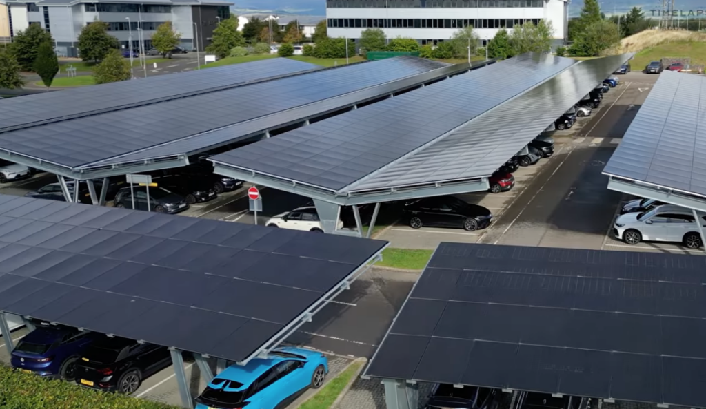 A parking lot with several rows of solar panel canopies providing shade for parked cars.